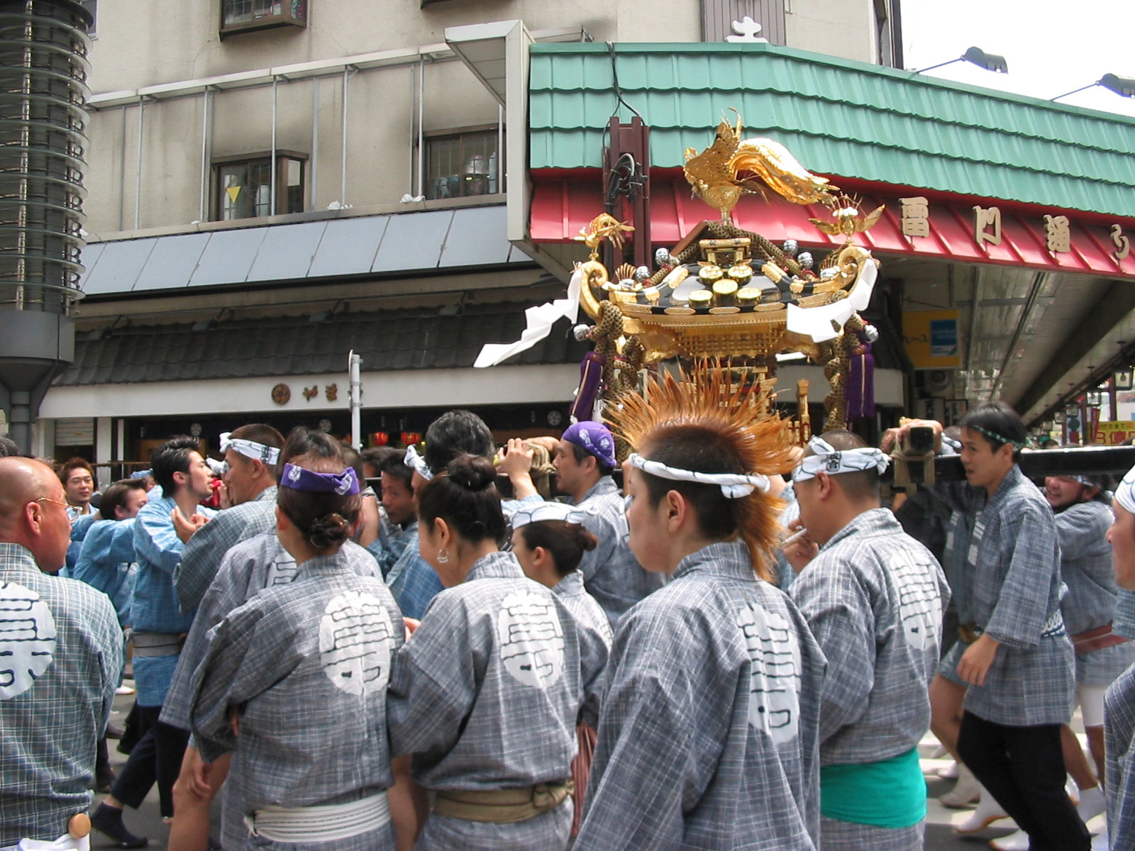 parade with men carrying golden shrine and one man with orange mohawk